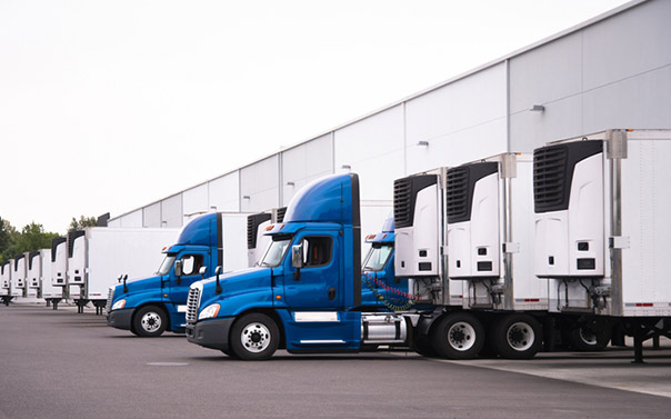 A fleet of blue semi truck at a warehouse