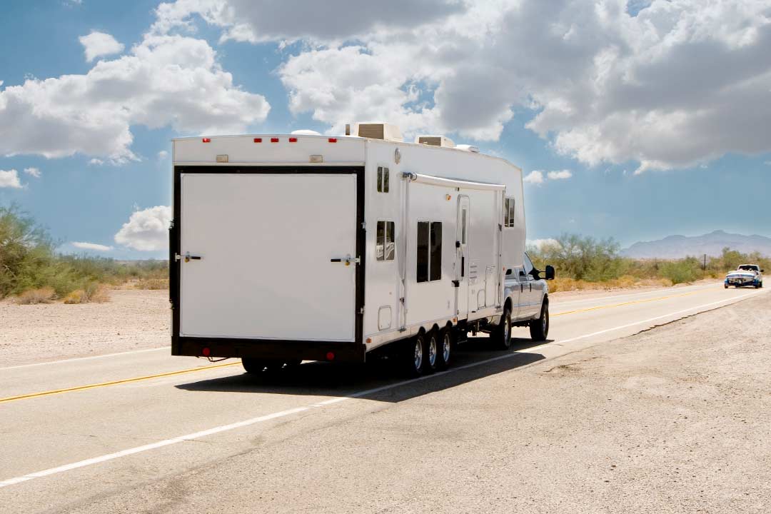 Ford F250 pulling a white toy hauler down the freeway