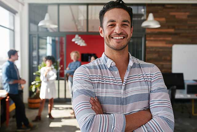 A young business person in office with team behind him